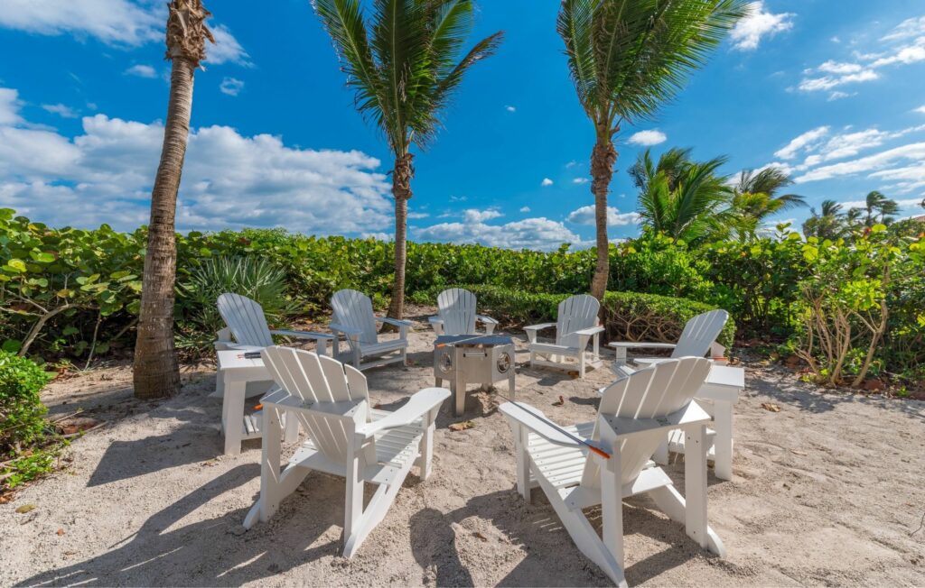Built to Last White Adirondack Chairs around a fire-pit grill on a sandy beach nook